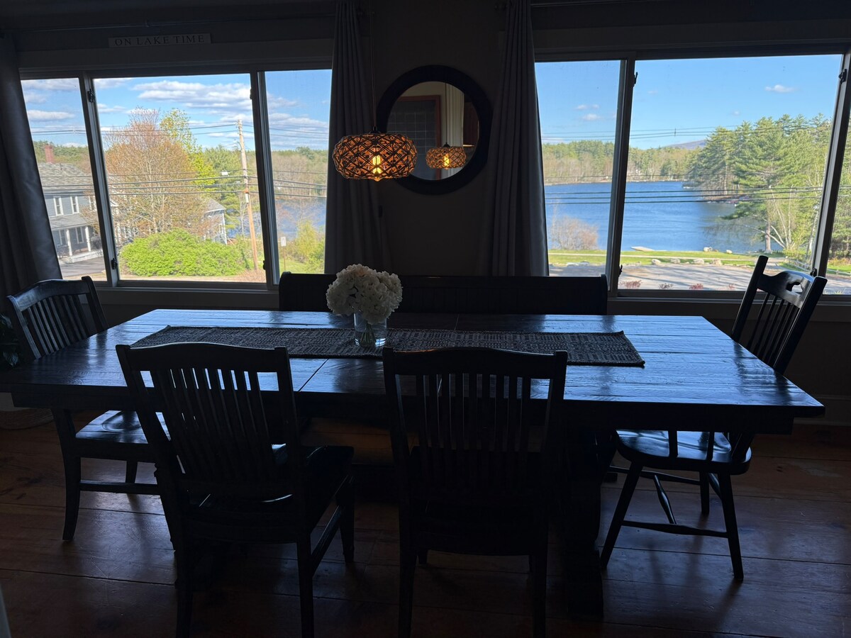 Long dining table framed by lake-view windows