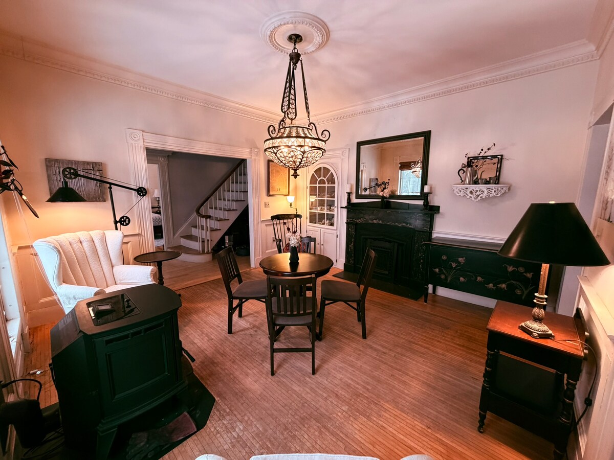 Fireside room with piano, chandelier, and stove